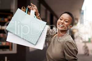 Who says happiness cant be bought. Portrait of an attractive young woman walking alone outside while shopping in the city.