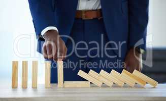 If ever you fall, well help pick up the pieces. Shot of an unrecognisable businessman working with falling wooden blocks.