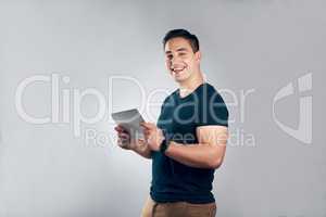 Downloading and upgrading apps with just a click. Studio shot of a handsome young man posing with a tablet against a grey background.