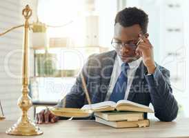 Reading up on an important case. Shot of a young male lawyer reading a book at work.