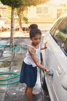 Shes so young but helpful. Shot of a young girl busy cleaning a car outside.