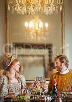 Its been a grand harvest in the kingdom. Shot of a noble couple toasting while eating together in the palace dining room.