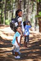 Teaching them Natural Science the old-fashioned way. Shot of a mother and her two children taking a walk in the woods.