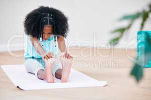 Treat your body well and it will reward you. Shot of a young girl practicing yoga at home.