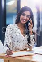 Im sealing another deal right now. Portrait of a beautiful young businesswoman taking a call on a cellphone in a modern office.