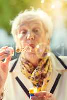 Shes a golden oldie. Shot of a fun-loving senior woman blowing bubbles outside on a sunny day.