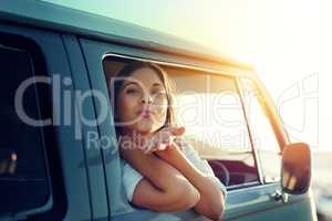 Mwah See ya when I get back. Shot of a young woman leaning out of a vans window and blowing a kiss on a roadtrip.