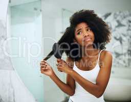 Struggle with dry, brittle hair. Shot of an attractive young woman struggling to comb her hair at home.
