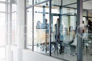 It all begins in the boardroom. Full length shot of a business meeting taking place in a glass-walled boardroom.