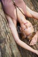 Finding peace in nature. A young woman lying down with her eyes closed on the forest floor.