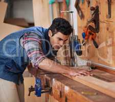 Details make the difference. Shot of a focused handyman measuring a piece of wood while working in his workshop.