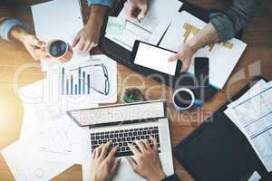 More gets done by working efficiently together. High angle shot of a group of unrecognisable businesspeople working together in an office.