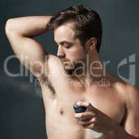 24 hour protection. Cropped shot of a handsome young man spraying deodorant on his armpit.