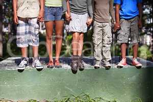 Friendship, diversity and nature. Cropped shot of four kids standing on a cement block outdoors.