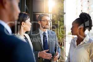 They never question his ideas. Shot of a diverse group of businesspeople having a meeting on a balcony in bright sunlight.