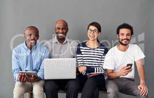 Technology is something we all have in common. Studio shot of businesspeople using wireless technology against a gray background.