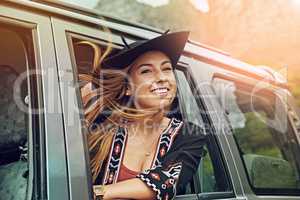 Just enjoy the journey of life. Cropped shot of a young woman leaning out the window of a car while on a roadtrip.