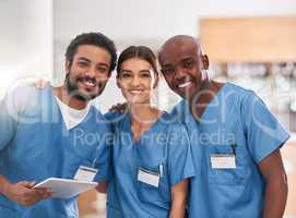 They are young but they are experienced. Portrait of a group of cheerful young doctors standing together with a digital tablet inside of a hospital.