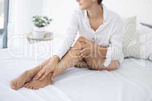 Silky smooth. Cropped shot of an unrecognizable young woman rubbing her silky soft legs while sitting on her bed at home.