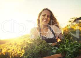 I grew it organically. Shot of a young woman holding a crate full of freshly picked produce on a farm.