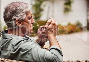 Time to light up. Cropped shot of a relaxed senior man smoking a marijuana joint on his own inside of his garden at home during the day.