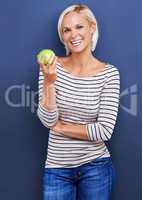 Snacking with a smile. Studio shot of an attractive young woman holding an apple.