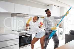 The difference between ordinary and extraordinary is a little extra. Shot of a happy young couple having fun while cleaning the kitchen at home.