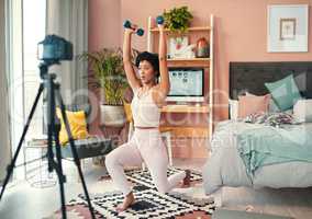 Documenting her transformative fitness journey. Shot of a young woman recording herself while exercising at home.
