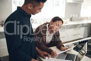 Taking a look at how they spent money for the money. Shot of a young couple going through paperwork while using a laptop at home.
