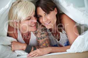 Sharing a special moment. Portrait of a loving lesbian couple lying in bed.