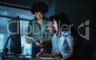 At the core of success is commitment. Shot of a group of young businesspeople using a digital tablet and computer during a late night at work.