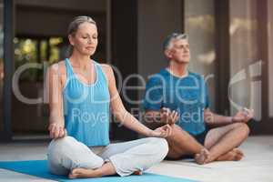 Peace comes within. Shot of a mature couple calmly engaging in a yoga pose with their legs crossed.