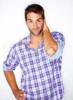 Casual modern charm. Handsome young guy in a check shirt with his hand behind his head against a white background.