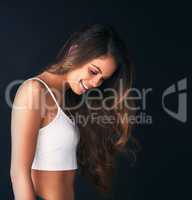 Her hairs got amazing volume. Studio shot of an attractive young woman posing against a dark background.