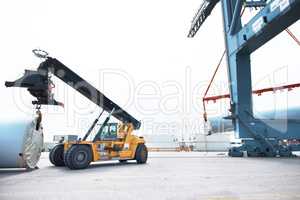 We handle the goods. A loader in a vehicle handling cargo in an industrial area.