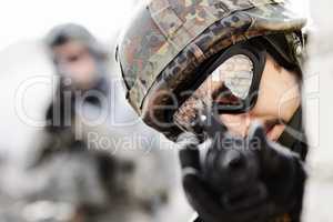 Eagle eyed shooter. Close up of a sniper with gun pointed at the camera and soldier in the background with copy space.