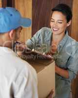 Fast and friendly service. Shot of a young woman standing at her front door signing for a package from a courier.