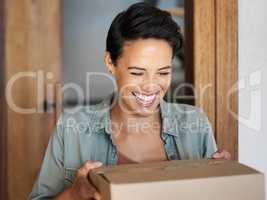 Delivered on time every time. Shot of a smiling young woman standing at her front door receiving a package from a courier.