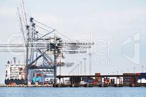 Gantry Cranes in a harbor. A photo of a harbor with anchored ships, gantry cranes and containers..