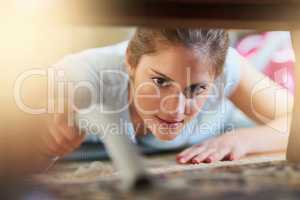 Cleaning those hard to reach places. Closeup shot of a young woman vacuuming underneath a piece of furniture.