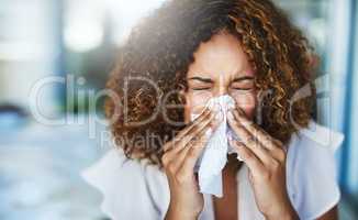 I think Im going to the doctor later. Shot of a frustrated businesswoman using a tissue to sneeze in while being seated in the office.