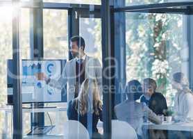 Teamwork divides the task and multiplies the success. Shot of a businessman presenting information on a monitor in the office to a group of businesspeople.