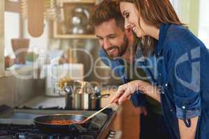 They like their meals home cooked and hearty. Shot of a happy young couple cooking a meal together on the stove at home.