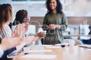 She deserves all the praise in the world. Low angle shot of a group of businesspeople applauding a colleague while sitting in the boardroom during a meeting.