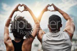 Happy hearts. Rearview shot of a sporty young couple making heart shapes with their hands while exercising outdoors.