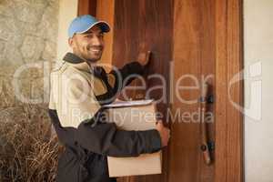 Getting your package delivered on time every time. Portrait of a smiling delivery man holding a package and knocking on a customers door.