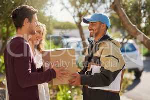 Delivery right to your door. Shot of a courier delivering a package to a smiling young couple at home.