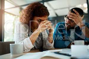 It feels like were starting to drown in debt. Shot of a young couple looking stressed out while working on their budget at home.
