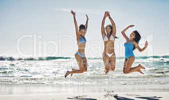 One of those crazy, carefree summers. Portrait of a group of happy young women jumping for joy at the beach.