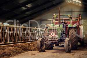 Old faithful. Shot of a rusty old tractor standing in an empty barn.